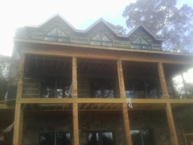 Dormers and porch framing on a large log home under construction — Roof Coating work by our crew in Micanopy