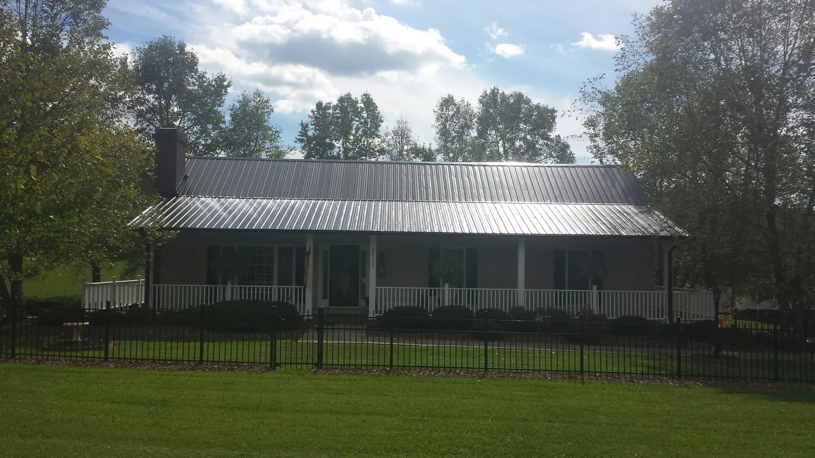 Gray metal roof on a brick ranch with a full width front porch — Gutter Guard Installation work by our crew in Micanopy