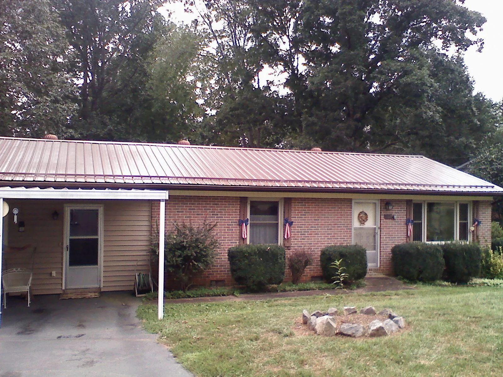 Bronze metal roof and carport on a brick ranch home — Roof Repair work by our crew in Micanopy