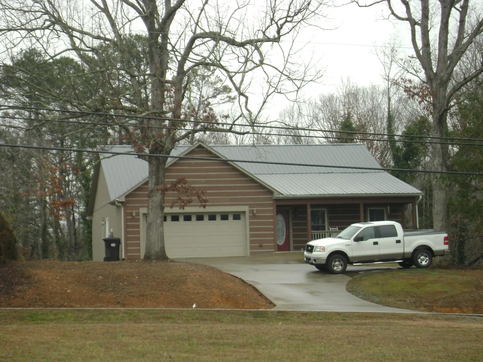 Gray metal roof on a log sided house with an attached two car garage in Micanopy